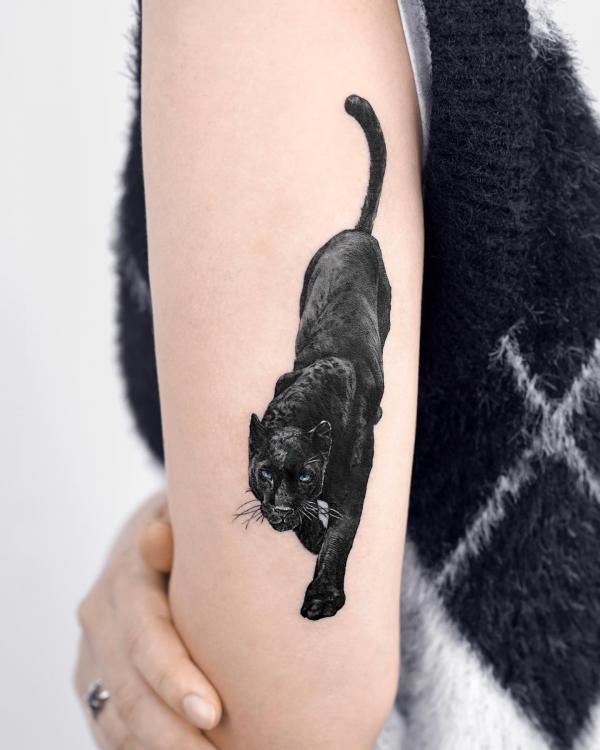 Realistic black walking panther tattoo on upper arm