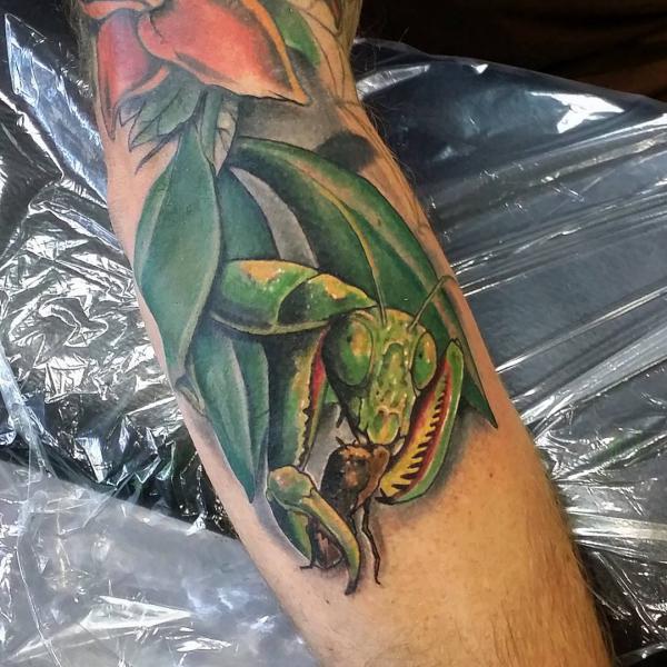 Realistic praying mantis eating tattoo