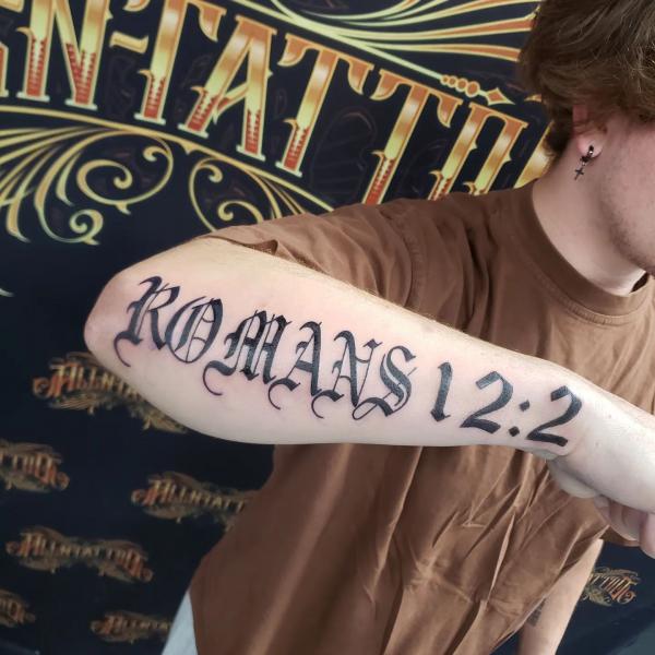 Romans 12 2 lettering tattoo forearm
