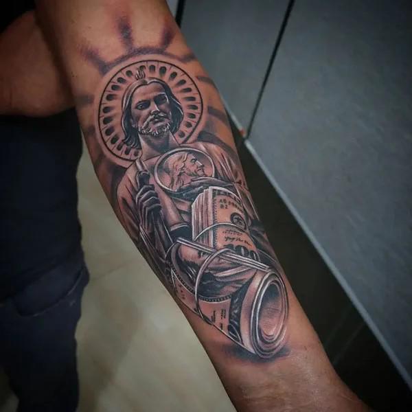 San Judas and money inner forearm tattoo