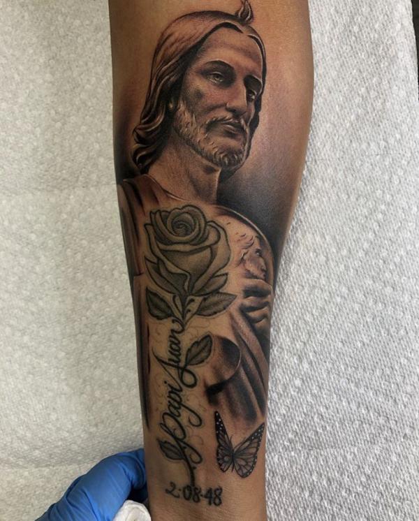 San Judas and rose with name and date tattoo