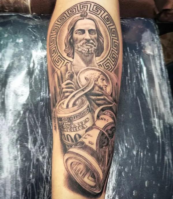 San Judas with Greek key and money forearm tattoo