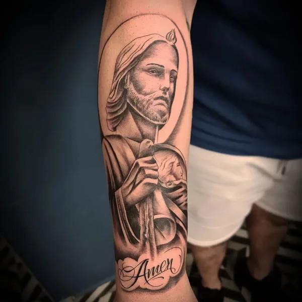 San Judas with word Amen forearm tattoo