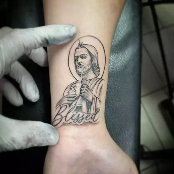 Small San Judas wrist tattoo black and grey