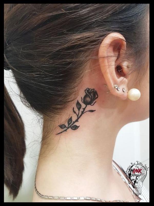 Small black rose with thorns tattoo on the side of neck