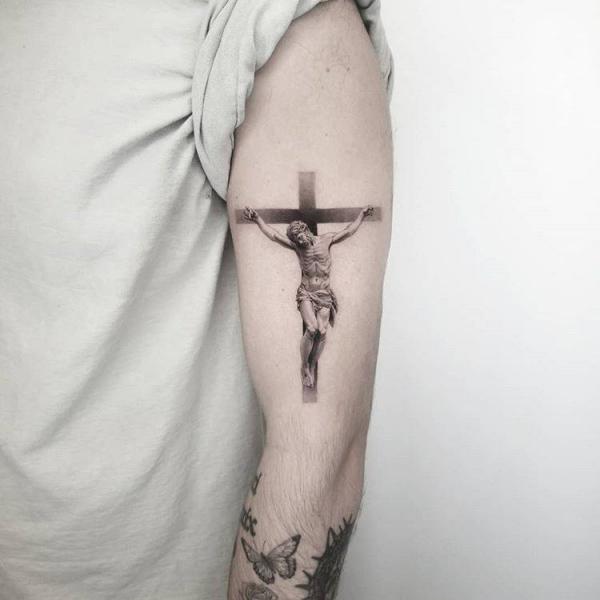 Small cross tattoo with jesus on upper arm