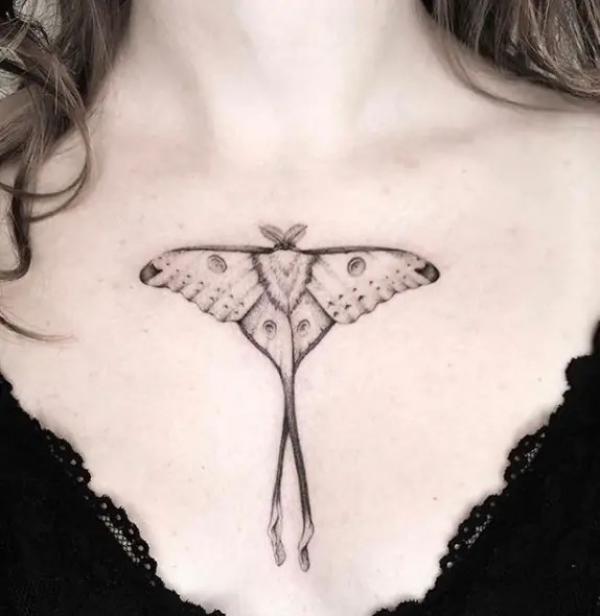 Small luna moth above boob tattoo black and grey