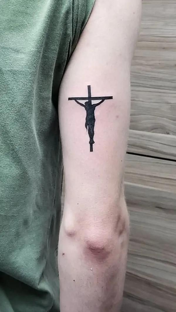 Small silhouette cross tattoo with jesus on upper arm