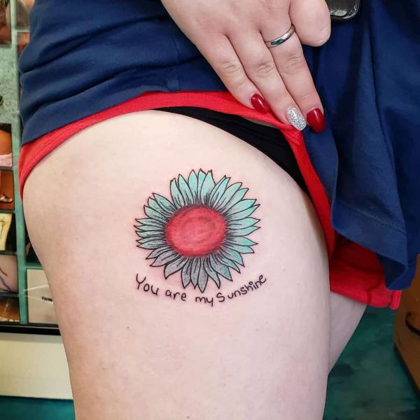 Small sunflower with words you are my sunshine tattoo on thigh