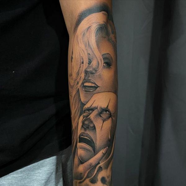 Smile face and cry mask forearm tattoo
