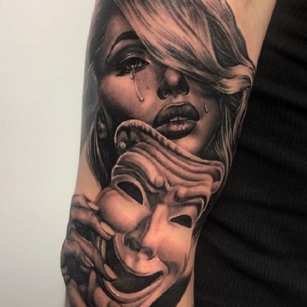Smile mask and cry face tattoo on arm