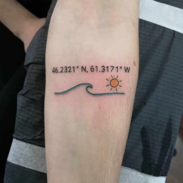 Tiny wave and sun with coordinates tattoo below inner elbow