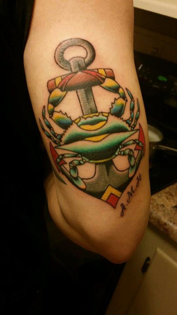Traditional anchor and Zodiac cancer tattoo on back of arm
