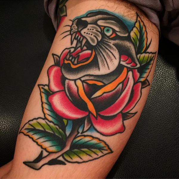 Traditional panther head with rose bicep tattoo