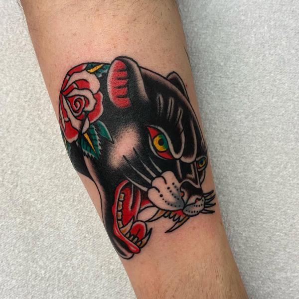 Traditional panther head with rose tattoo on forearm