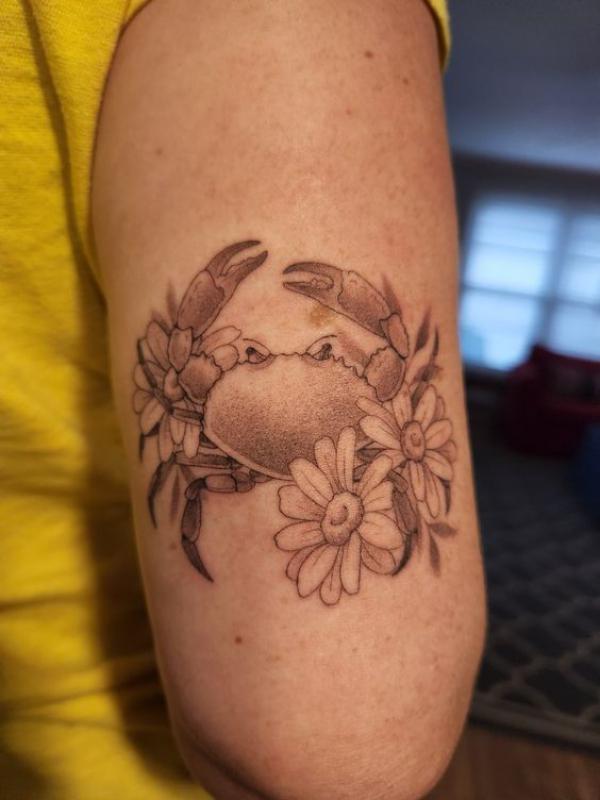Zodiac cancer crab and daisy tattoo above elbow