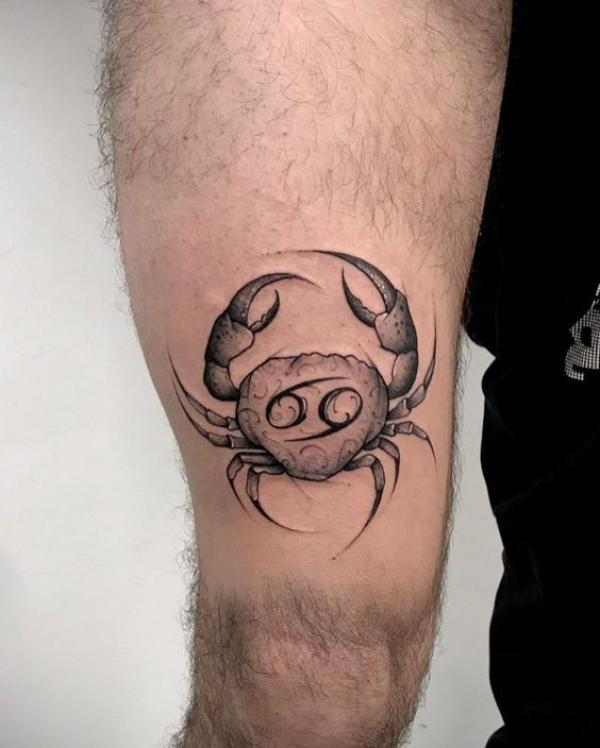 Zodiac cancer with glyph tattoo above knee