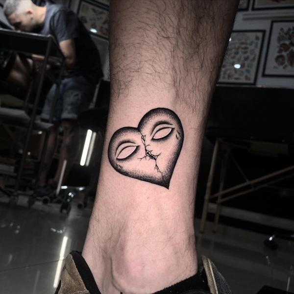 broken heart with eyes tattoo above ankle
