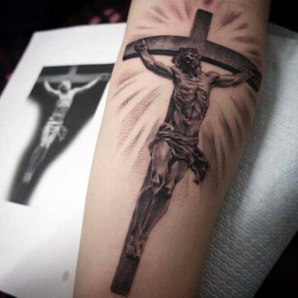 cross tattoo with jesus and halo on forearm