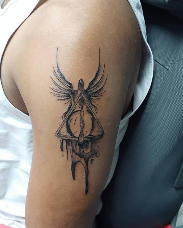 deathly hallows with wings tattoo on upper arm