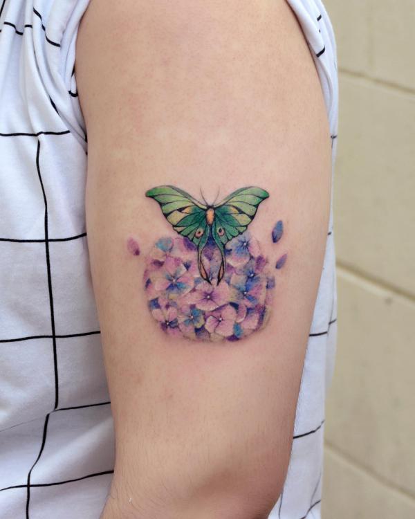 luna moth and flowers upper arm tattoo
