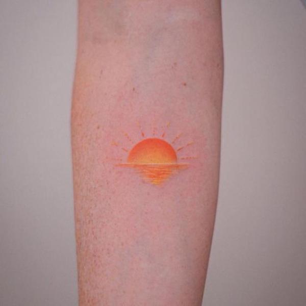 Brown sunrise tattoo below inner elbow