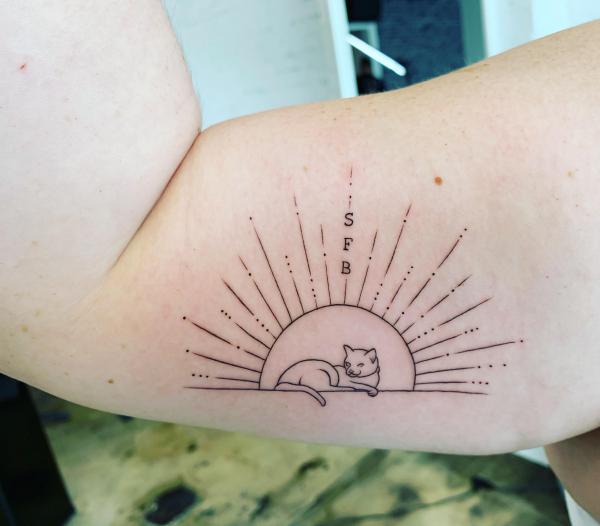 Half sun and cat line work tattoo on bicep