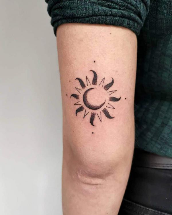 Moon in sun tattoo above elbow