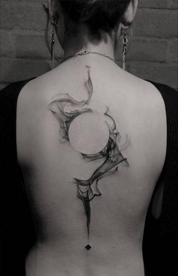 Negative space circle surrounded by smoke back tattoo