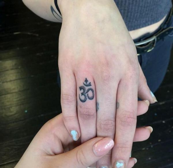 OM ring finger tattoo