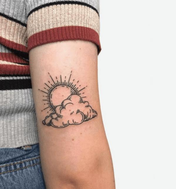 Simple rising sun and clouds tattoo above elbow