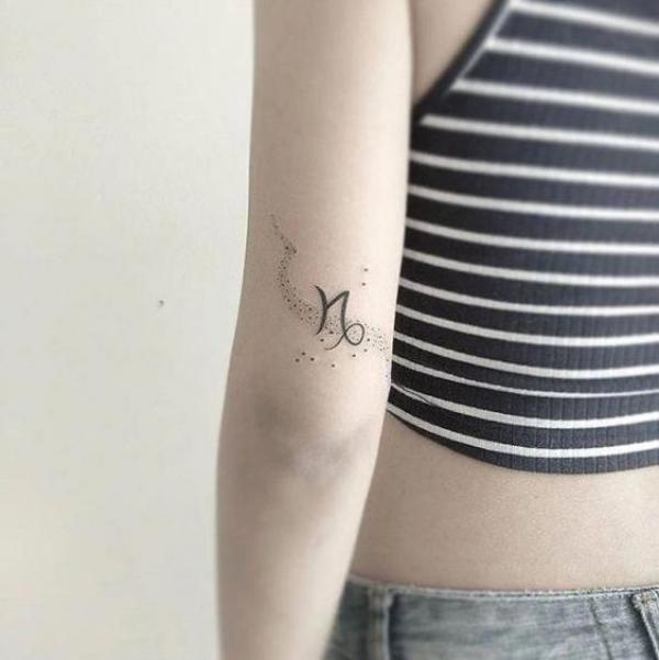 Small Capricorn sign tattoo above the elbow