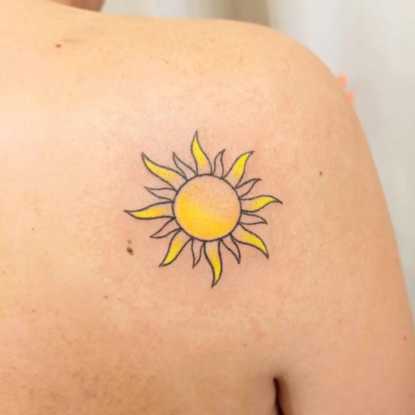 Small sun outline tattoo on shoulder blade