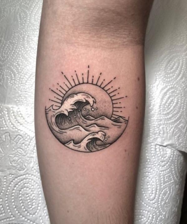 Sun and wave tattoo on inner forearm
