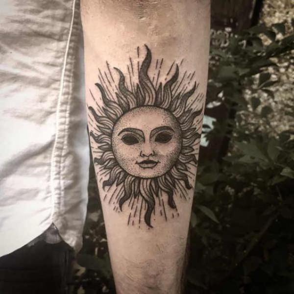 Sun face tattoo on inner forearm