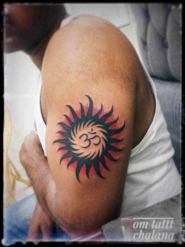 Sun with OM symbol tattoo on upper arm