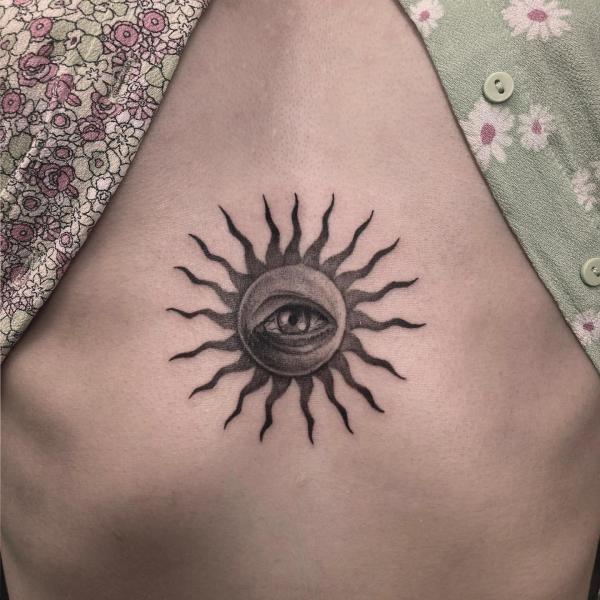 Sun with eye under boob tattoo