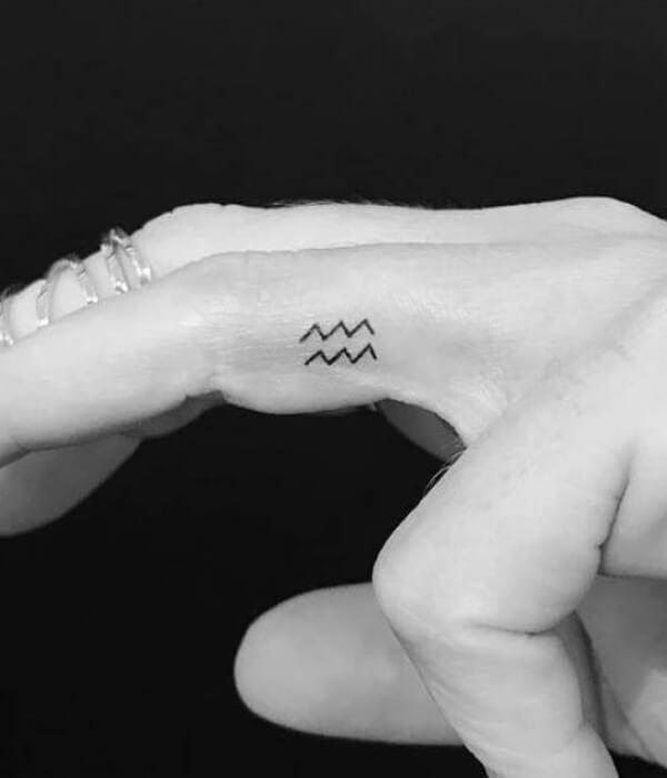 Tiny Aquarius finger tattoo