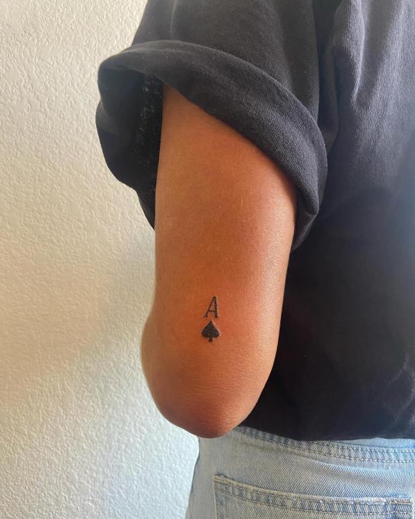 Tiny ace of spade tattoo above elbow