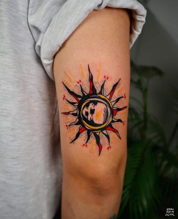 Watercolor sun tattoo above elbow