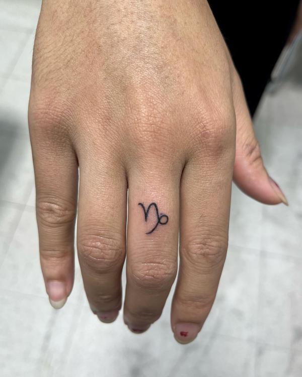 capricorn glyph tattoo on the middle finger