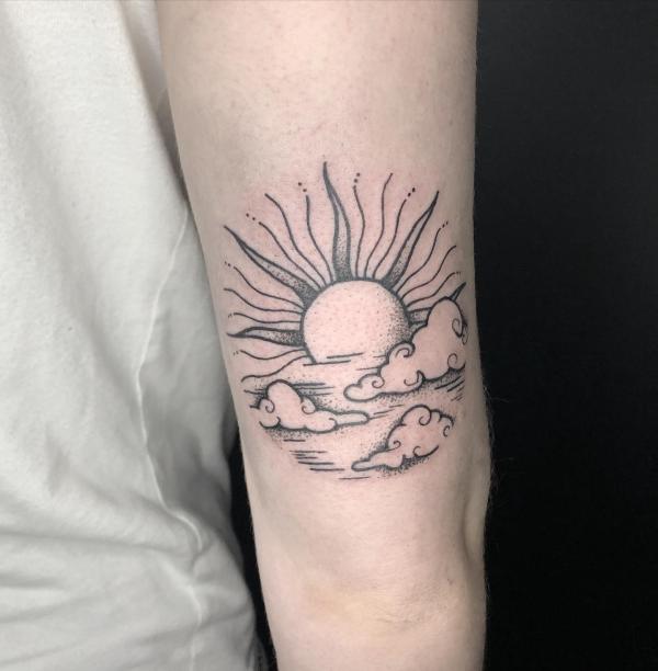 sun and clouds tattoo above elbow