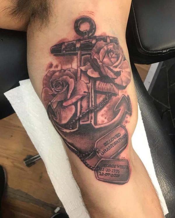 Anchor with roses and dog tag tattoo on bicep