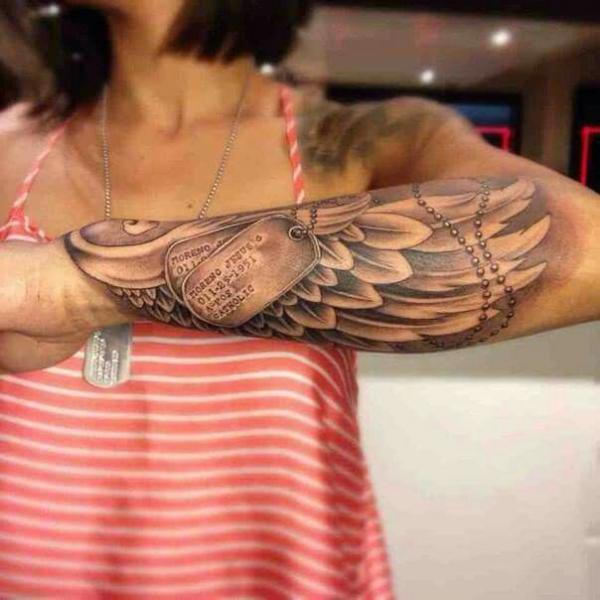 Angel wings and dog tag forearm tattoo