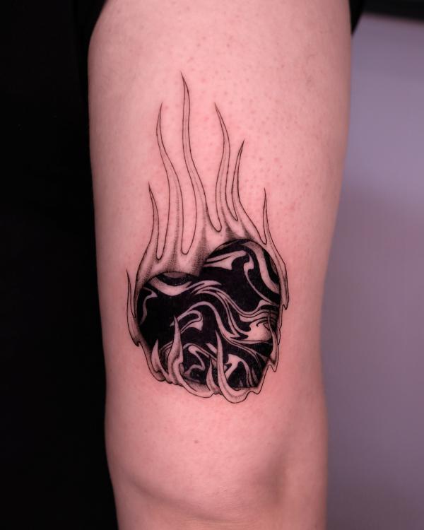 Black and white heart in flame tattoo above elbow