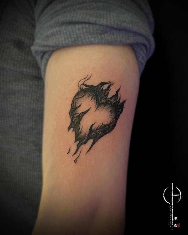 Black and white heart in flame tattoo on upper arm