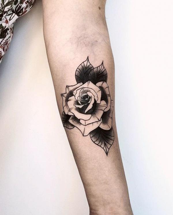 Black and white rose tattoo on forearm