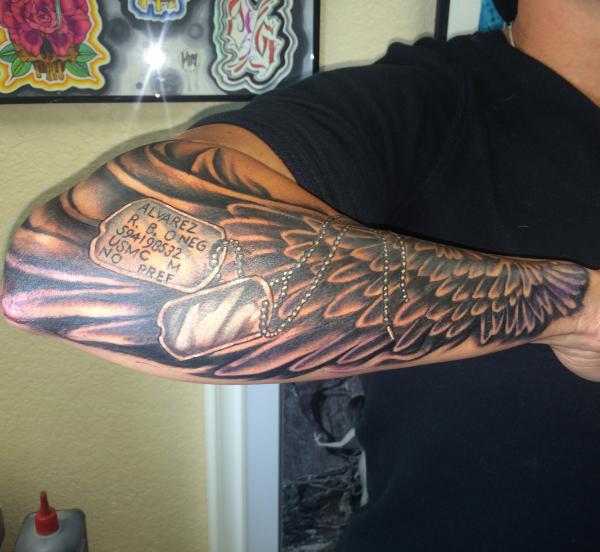 Dog tag and wings tattoo forearm