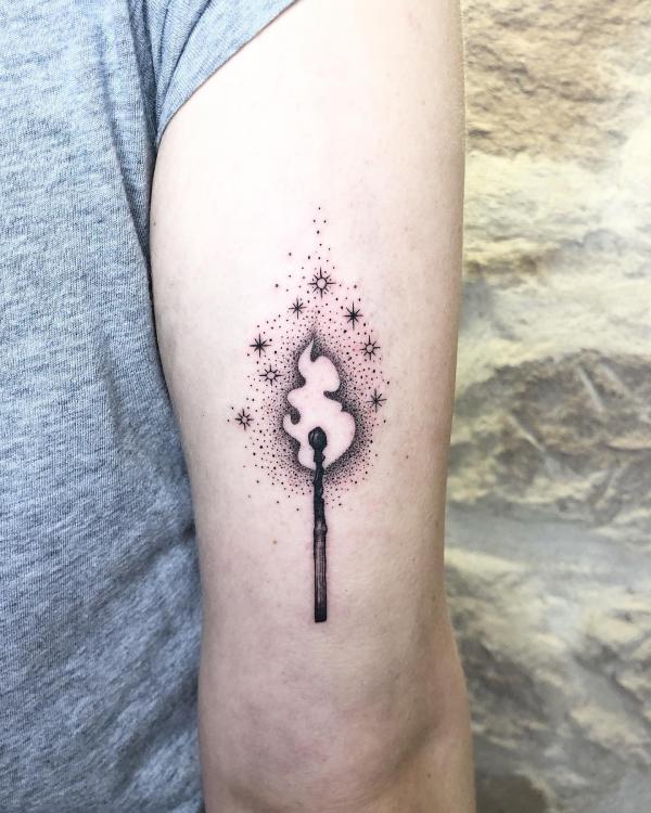 Match lit flame with stars tattoo on back of arm