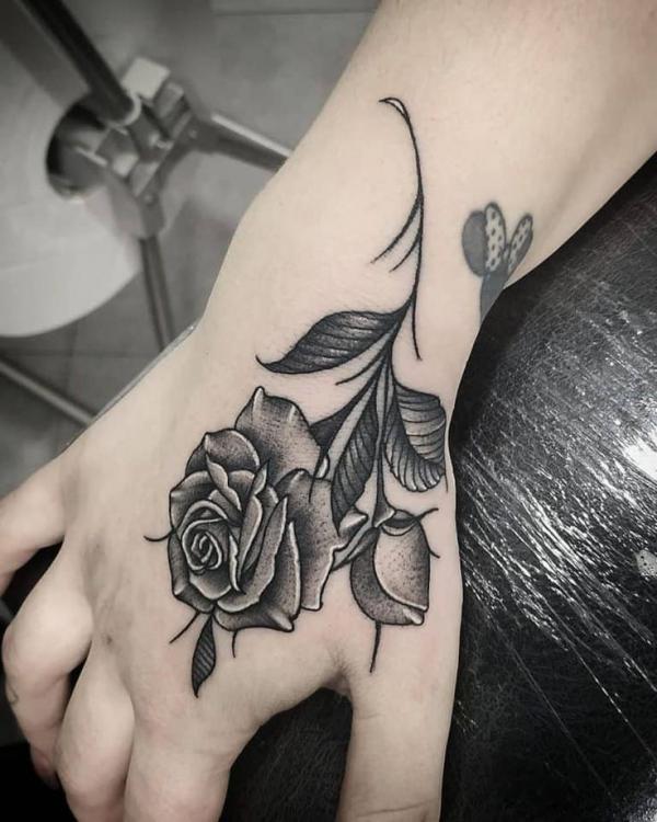 Small black and white rose tattoo on hand